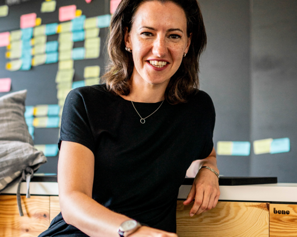 Claudia Feiner sitzt vor einer Tafel mit Postits; Text:'Moderne Arbeitswelten'