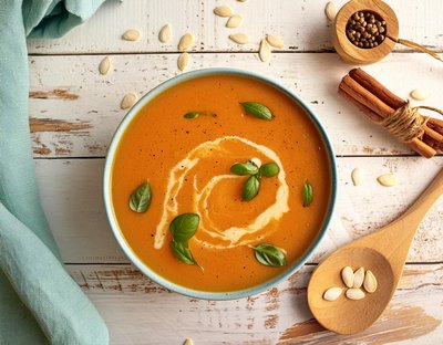 Mit Firefly generiertes Bild: Schüssel mit Tomatensuppe, verziert mit Sahne und Basilikumblättern auf einem Holztisch